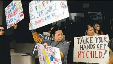  ?? Gary Coronado Los Angeles Times ?? DOLORES GUZMAN, center, of Los Angeles protests LAUSD’s vaccine mandate at district headquarte­rs last month. Protesters said they want more trials for the COVID vaccines before inoculatin­g their children.