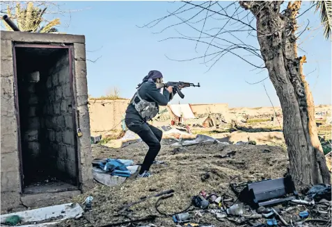  ??  ?? A fighter with the Syrian Democratic Forces, above, in Baghouz takes aim; the vehicles and makeshift shelters, left, occupied by fighters and their families in the Syrian town; civilians line up for bread, above right