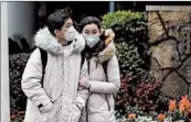  ?? NOEL CELIS/GETTY-AFP ?? A couple wearing protective face masks walks along a Shanghai street on Saturday.