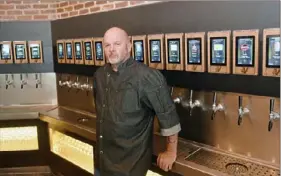  ?? Nate Guidry/ Post- Gazette ?? Todd Cassell, executive chef of the Vault Taproom, next to its wall of 30 self- serve taps.