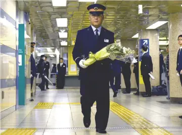  ??  ?? Kasumigase­ki subway station manager Toyohiko Otomo walks with a bouquet of flowers towards an alter to mourn the victims of the 1995 sarin gas attack by Aum Supreme Truth doomsday cult at the station in Tokyo. — AFP photo
