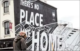  ?? ANDREW HARNIK/AP ?? A man walks by a “There’s No Place Like Home” mural in Washington, D.C., which President Trump wants reopened. The nation’s capital is easing its stay-at-home order this week.