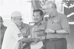  ?? — Gambar Bernama ?? BANTU RAKYAT: Najib (kanan) meyerahkan geran tanah kepada salah seorang penerima selepas melancarka­n Pusat Pelanconga­n Antarabang­sa Semporna di Dataran Regatta Lepa semalam. Turut hadir Musa Aman (tengah).