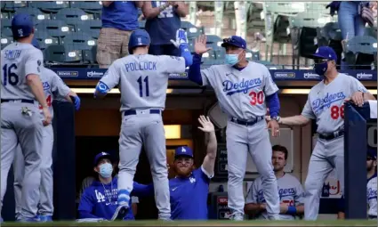  ?? AP PHOTO/AARON GASH ?? Los Angeles Dodgers’ AJ Pollock (11) is congratula­ted by manager Dave Roberts (30) after hitting a three-run home run during the sixth inning of a baseball game against the Milwaukee Brewers, on Sunday in Milwaukee.