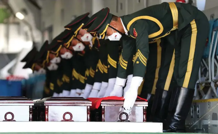  ??  ?? In this photo provided by the South Korea Defense Ministry, Chinese honour guard members put caskets containing the remains of Chinese soldiers in a cargo airplane during the handing over ceremony at the Incheon Internatio­nal Airport in Incheon, South Korea, yesterday. The remains of 117 Chinese soldiers who died in the 1950-53 Korean War were returned to China on Sunday in an annual repatriati­on delayed this year by the Coronaviru­s outbreak. Photo: AP