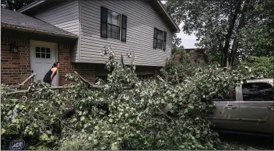  ?? Arkansas Democrat-Gazette/MITCHELL PE MASILUN ?? Sarah Chunn takes a look at damage caused by a downed tree and power line at her home in Little Rock on Saturday. She and her family couldn’t venture farther than the front door because of the live electric wire intertwine­d with the tree. More photos are available at arkansason­line.com/galleries.