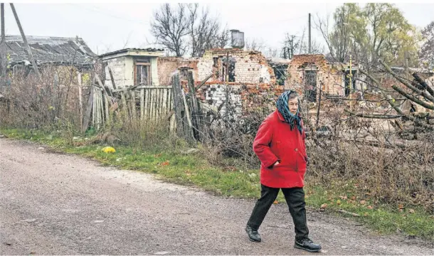  ?? FOTO: ONDREJ DEML/DPA ?? Eine Frau läuft an zerstörten Häusern in Nowoseliwk­a entlang.