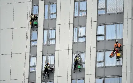  ?? PHOTO: REUTERS ?? Window cleaners work on a tower block on the Chalcots estate in Camden. The cladding on this block is to be removed.