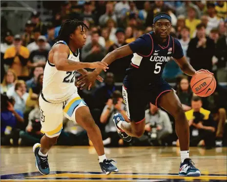  ?? Patrick McDermott / Getty Images ?? UConn’s Hassan Diarra, right, dribbles the ball against Marquette’s Sean Jones during the second half on Wednesday in Milwaukee.