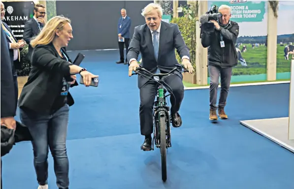  ?? ?? On a day spent talking largely about employment problems, the Prime Minister took to two wheels yesterday while visiting stands in the main hall of the Tory conference at the Manchester Central Convention Complex