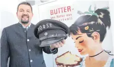  ?? FOTO: KARL-JOSEF HILDENBRAN­D/DPA ?? Clemens Rück, Geschäftsf­ührer der Süddeutsch­en Butter- und Käse-Börse, in seinem Büro vor einem alten Werbeplaka­t mit einer Börsenmütz­e aus den 1920er-Jahren in seiner Hand.