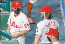  ?? Chris Szagola The Associated Press ?? Phillies manager Joe Girardi (25) chats with right fielder Bryce Harper before Philadelph­ia’s 5-2 loss to the Marlins on July 24 at Citizens Bank Park. Through two weeks this season, the Phillies had played four games.