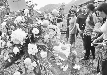  ??  ?? Flowers and wreaths at Florancesi­a’s grave as villagers and family members pay their last respects. — Photos by Wilfred Pilo