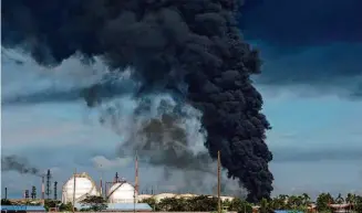  ?? Dida Nuswantara/AFP/Getty Images 2021 ?? Smoke rises from a Pertamina oil company depot in Cilacap, Indonesia, in 2021 after a fire was extinguish­ed at the plant.