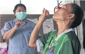  ?? CHATPATTAR­ASILL PATTARAPON­G ?? A medic in Pathum Thani teaches a woman to use an antigen test kit in September. Local healthcare centres are now being run by Provincial Administra­tive Organisati­ons.