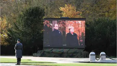  ??  ?? A German bugler stands ready near a big screen showing Merkel and Macron taking part in a French-German ceremony in the clearing of Rethondes (the Glade of the Armistice) in Compiegne, northern France, as part of commemorat­ions marking the 100th anniversar­y of the November 11, 1918 armistice that ended World War I.