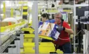  ?? TED S. WARREN / THE ASSOCIATED PRESS FILE ?? Mark Oldenburg processes outgoing orders at Amazon. com’s fulfillmen­t center in DuPont, Wash.