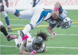  ?? GRAHAM HUGHES/THE CANADIAN PRESS ?? Montreal Alouettes’ quarterbac­k Troy Smith, top, leaps over Hamilton Tiger-Cats’ Rico Murray in Montreal’s win. Smith’s start may signal a new era for the Alouettes.