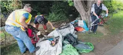  ??  ?? Bylaw officers and maintenanc­e crews remove tents and garbage from a wooded area on Dallas Road, near Douglas Street.