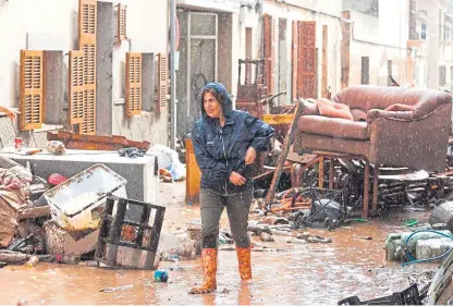  ?? Picture: AP. ?? A woman walks past damaged belongings in the pouring rain in Sant Llorenc.
