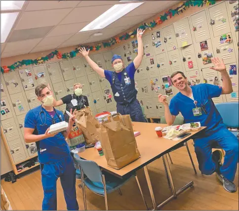  ?? (Courtesy Photo/Brittney Caldera) ?? Oregon Health & Science University nurses Nick Greenwood (from left), Callie Harling, Derrell Wheeler and Orion Meredith as they eat a meal delivered to the hospital’s frontline covid-19 health care workers in a break room at Oregon Health & Science University in Portland. The program that provided the meals, paid for by a grant from an Oregon-based insurance fund, recently expired but the hospital is hoping for new donations to reboot it as covid-19 variants could cause a new surge of cases.