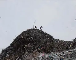  ??  ?? COLOMBO: Sri Lankan men walk back after erecting a white flag on top of a garbage mound following the garbage dump collapse in Meetotamul­la, on the outskirts of Colombo. —AP