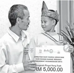  ??  ?? Hang Tuah Medal Award recipient Mohamad Syawal Mohd Shukri (right) and his father Mohd Syukri Muhamad Nor with his award medal, trophy and cheque for RM5,000 at a celebratio­n held in conjunctio­n with the national-levelWorld Senior Citizens’ and...