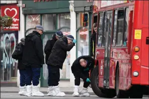  ?? (AP/Alberto Pezzali) ?? Police officers inspect a bus Monday as they work at the scene of Sunday’s attack in the Streatham neighborho­od of London.