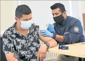  ?? NICOLAUS CZARNECKI / BOSTON HERALD FILE ?? Phamacist Essa Majrashi gives Oscar Ruiz his second dose of the coronaviru­s vaccine at the vaccinatio­n clinic inside the Chelsea Senior Center run by Cataldo Ambulance Service in Chelsea on June 5,