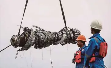  ?? REUTERS PIC ?? Search-andrescue officials looking on as a turbine engine of Lion Air Flight JT610 is lifted out of the sea in the north coast of Karawang, Indonesia, on Saturday.