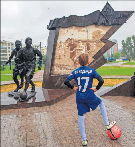  ??  ?? MONUMENTO. Un joven con un balón observa la estatua que recuerda el Partido del Sitio jugado en San Petersburg­o en 1942.