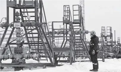  ?? VASILY FEDOSENKO ■ REUTERS FILE ?? An employee inspects a well head in the Yarakta oil field, owned by Irkutsk Oil Company, in the Irkutsk region of Russia.