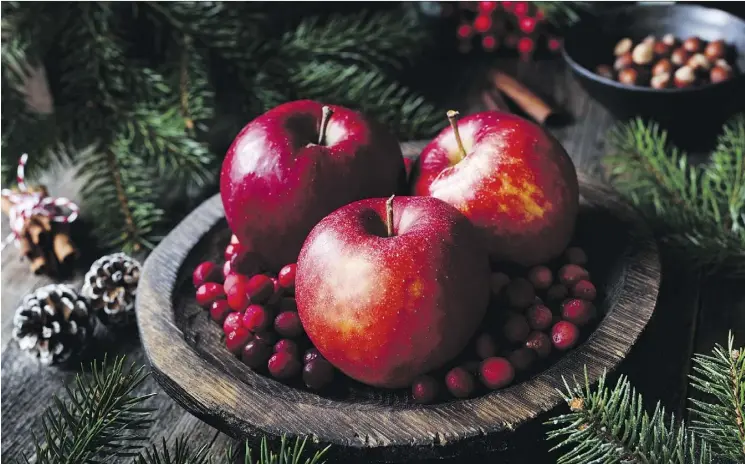  ?? GETTY IMAGES ?? Red apples, cranberrie­s and fir tree branches make a charming alternativ­e to the traditiona­l floral centrepiec­e.