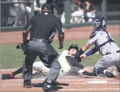  ?? PHOTOS BY JED JACOBSOHN — THE ASSOCIATED PRESS ?? The Giants’ Wilmer Flores is tagged out at home by the Rockies’ Tony Wolters during the second inning on Thursday in San Francisco.