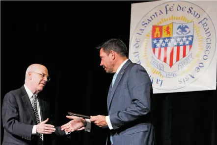  ?? LUIS SÁNCHEZ SATURNO/THE NEW MEXICAN ?? Mayor Alan Webber, left, shakes hands Monday with outgoing Mayor Javier Gonzales after Webber presented Gonzales with a gift during his inaugurati­on at the Santa Fe Community Convention Center.