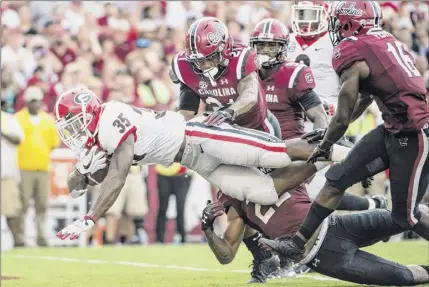  ?? Sean Rayford / Associated Press ?? Georgia running back Brian Herrien scores a touchdown against South Carolina during the second half of their game Saturday. Herrien finished with 45 yards on the ground on seven carries. The Bulldogs piled up 271 rushing yards in the victory while holding South Carolina to 54 yards on 20 carries.