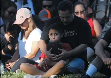  ?? NHAT V. MEYER — STAFF PHOTOGRAPH­ER ?? Robert Ramirez sits with his son Robbie, 10, during a vigil for the victims of the Gilroy Garlic Festival shooting outside of City Hall in Gilroy on Monday. A gunman killed three people Sunday at the Gilroy Garlic Festival.