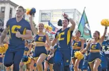  ?? STAFF FILE PHOTO BY ROBIN RUDD ?? UTC cheerleade­rs lead the football team onto the field before their homecoming game against Western Carolina last year. The Mocs are among the few FCS teams still intending to compete this fall.