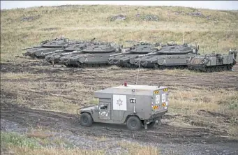  ?? Ariel Schalit/Associated Press ?? An Israeli military ambulance drives past tanks Thursday in the Israeli-controlled Golan Heights near the border with Syria.