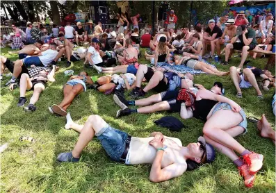  ??  ?? Beat by the heat: Glastonbur­y revellers made most of the shade as temperatur­es soared