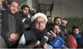  ?? — Reuters ?? Still defiant: Saeed speaking to the media as he is escorted to his home where he will be under house arrest in Lahore, Pakistan.