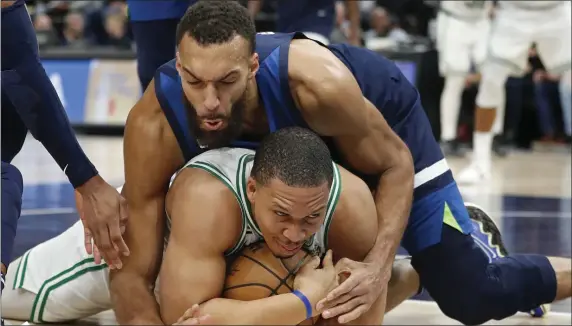  ?? BRUCE KLUCKHOHN — THE ASSOCIATED PRESS ?? Boston Celtics forward Grant Williams, bottom, grabs for the ball as Minnesota Timberwolv­es center Rudy Gobert forces a jump-ball call during the fourth quarter. The Celtics won, 104-102.