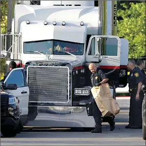  ?? AP/ERIC GAY ?? San Antonio police officers investigat­e the scene where people were found dead on Sunday in a tractor-trailer outside a Wal-Mart store in stifling summer heat.