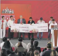  ??  ?? El presidente Andrés Manuel López Obrador entrega cheques a dos municipios de Oaxaca, resultado de lo recaudado en una subasta