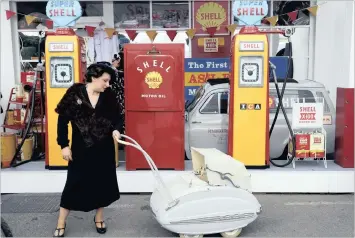  ?? PHOTO: REUTERS ?? A woman holds the handle of an old pram in front of vintage Shell petrol pumps at the annual Goodwood Revival historic motor racing festival, near Chichester, Britain. Royal Dutch/Shell and BP yesterday reported higher than expected earnings.