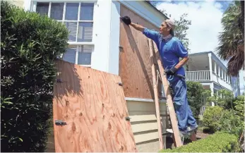  ?? GABE HERNANDEZ, USA TODAY NETWORK ?? David Montes boards up windows at a home in Corpus Christi, Texas, as the National Weather Service warned that the forecast for Hurricane Harvey “continues to grow more dire.”