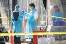  ?? Jessica Christian / The Chronicle ?? Medical staff conduct a test at a drivethrou­gh site at a Kaiser Permanente campus in San Francisco in March.