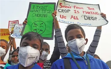  ?? (AFP) ?? Children wearing masks hold placards during a protest against air pollution, in New Delhi on Tuesday