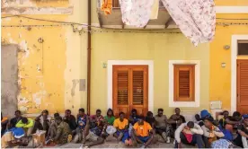  ?? ?? Migrants resting on the streets of Lampedusa. The island is about 70 miles from the coast of north Africa, where the smugglers operate. Photograph: Roberto Salomone/The Guardian