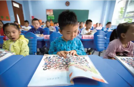  ??  ?? Primary students read a new Chinese textbook in Taiyuan, Shanxi Province, September 1, 2017